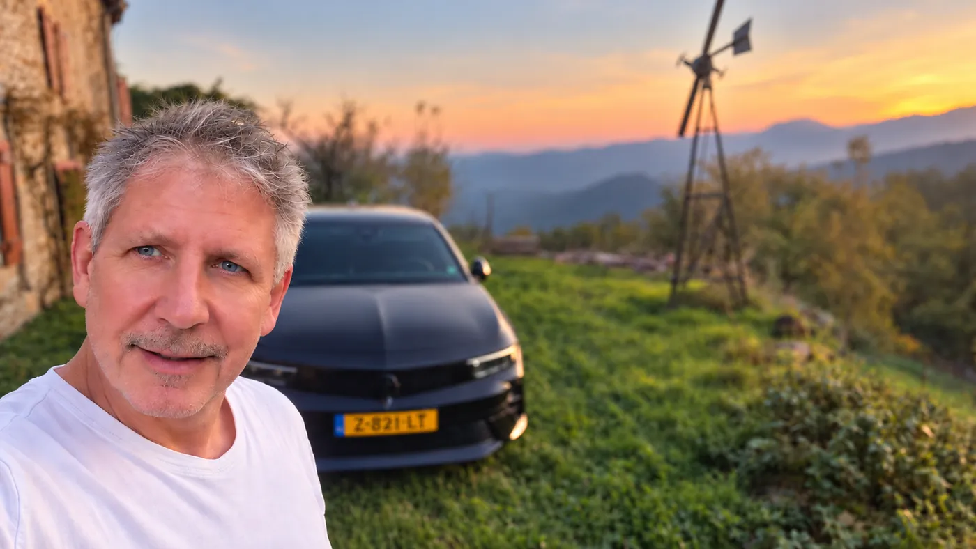 Vanuit Frankrijk Matthijs van Bright Online Company, buiten bij zijn auto met een windmolen op de achtergrond